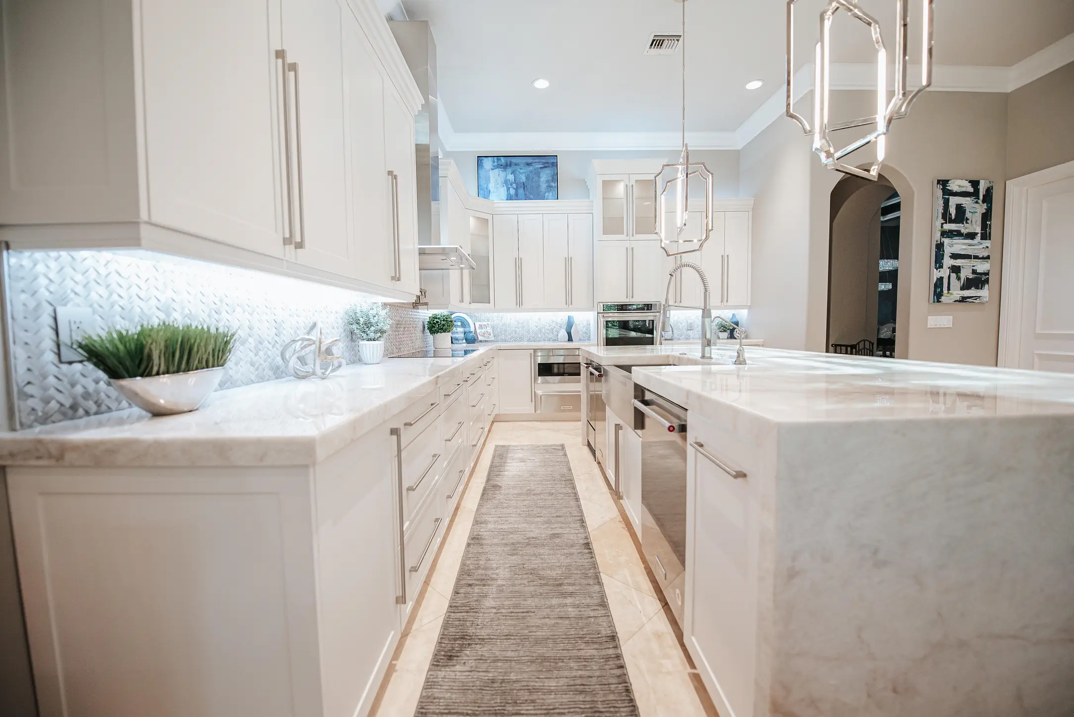 Modern white kitchen with quartz countertops, subway tile backsplash, and geometric pendant lights in luxury Fort Lauderdale home