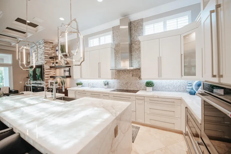 Modern white kitchen with marble countertops, geometric pendant lights, mosaic backsplash by YOLO Interiors Fort Lauderdale