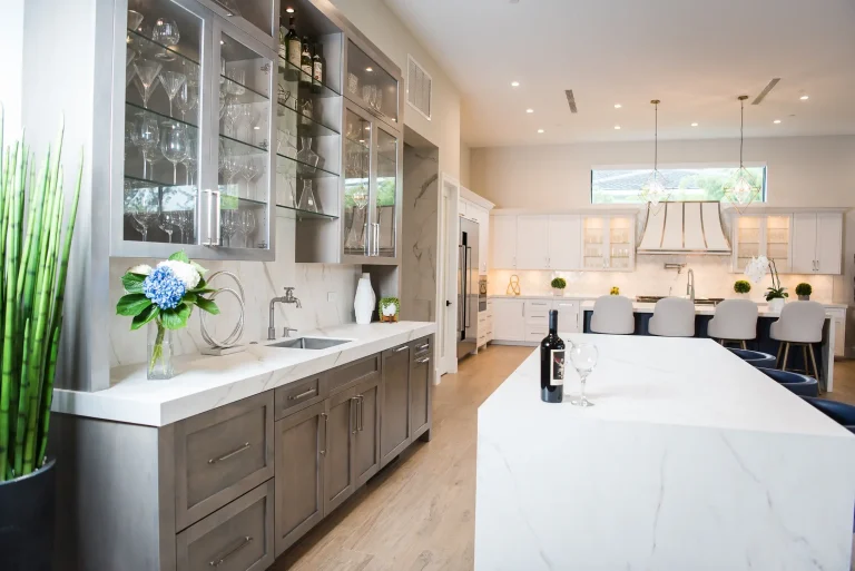 Modern luxury kitchen with gray cabinets, white quartz countertops, glass front upper cabinets, and marble backsplash in Fort Lauderdale home