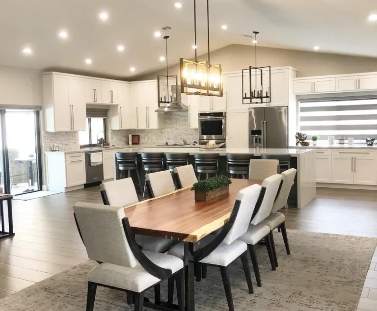 Modern open concept kitchen dining room with white cabinets, quartz island, wood dining table, pendant lights