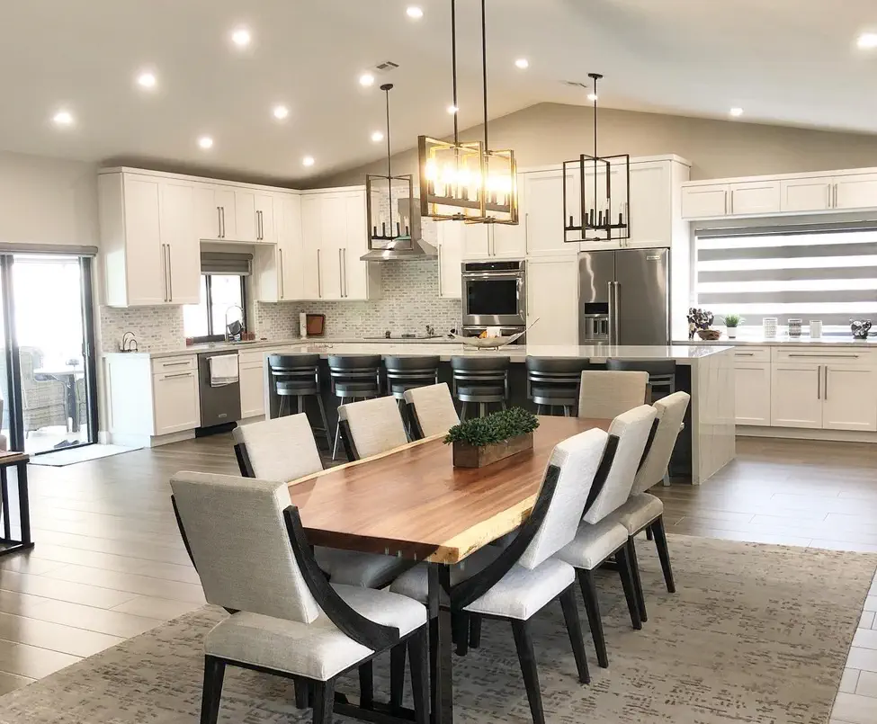 Modern open concept kitchen dining room with white cabinets, quartz island, wood dining table, pendant lights