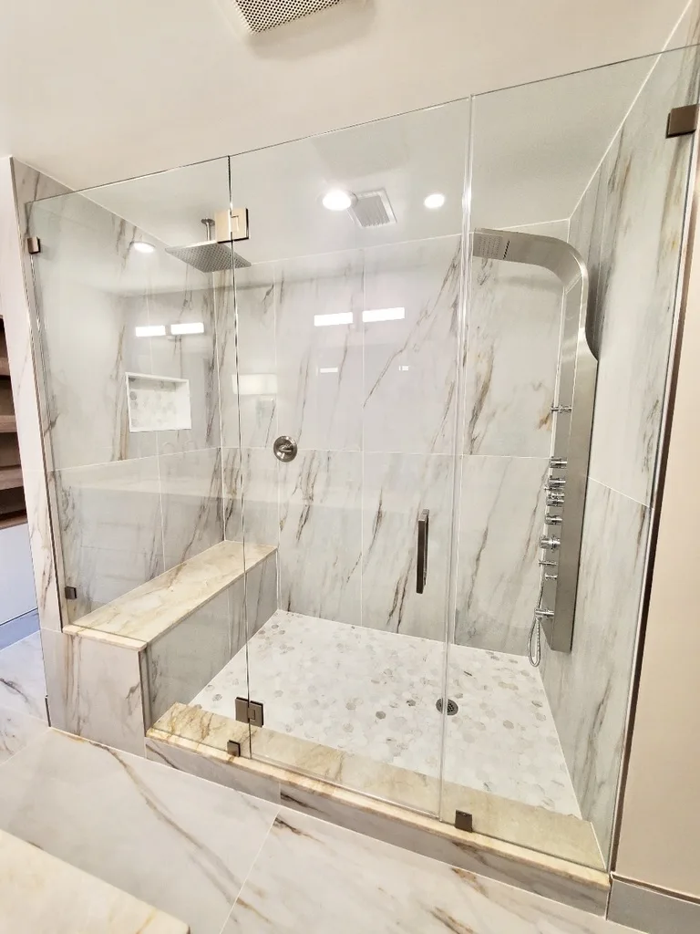 Luxury marble shower with glass enclosure and built-in bench, modern bathroom renovation Fort Lauderdale